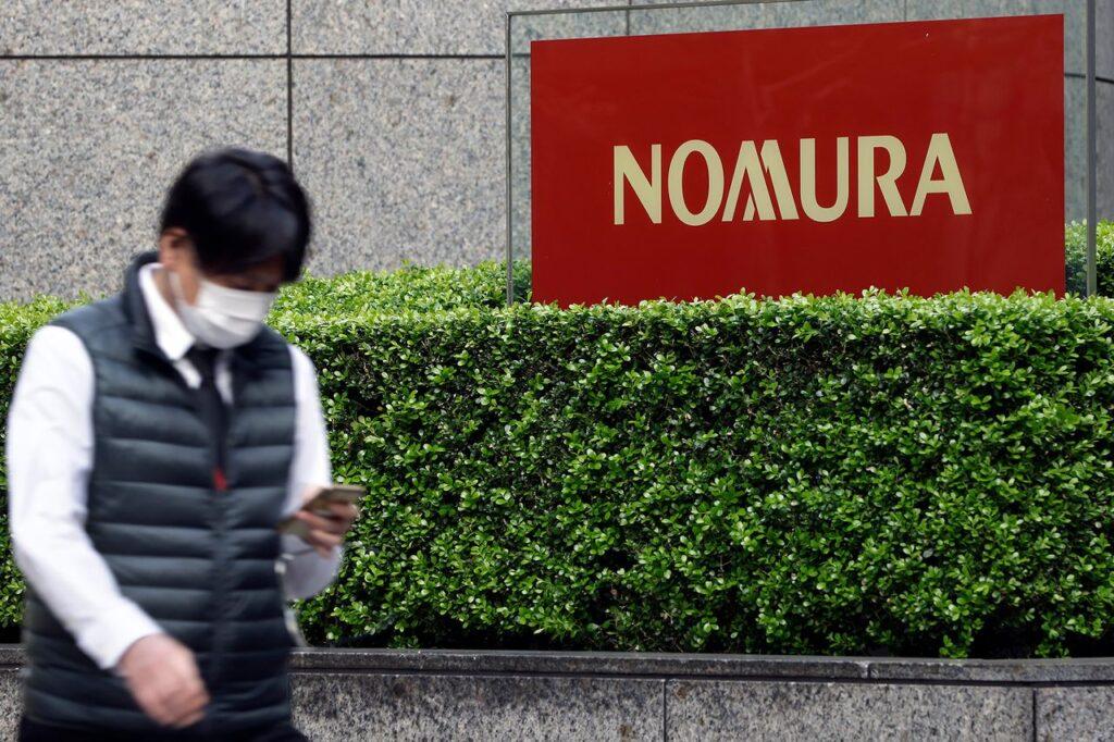 A pedestrian wearing a protective face mask walks past the Nomura Holdings Inc. signage outside its headquarters in Tokyo, Japan, on Monday, March 29, 2021. Photo: Getty Images